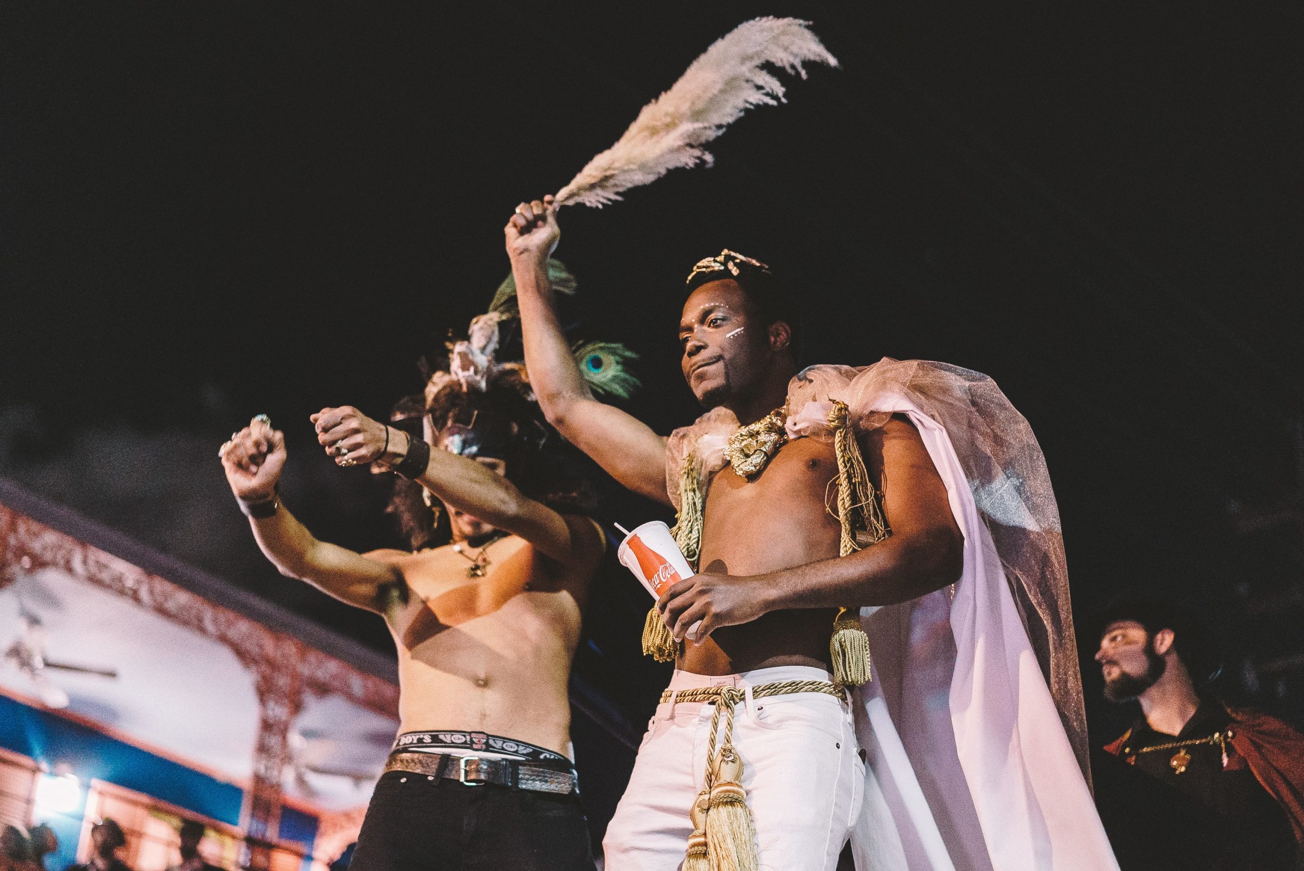 Masqueraders with hands raised on top of a colorful Carnival float