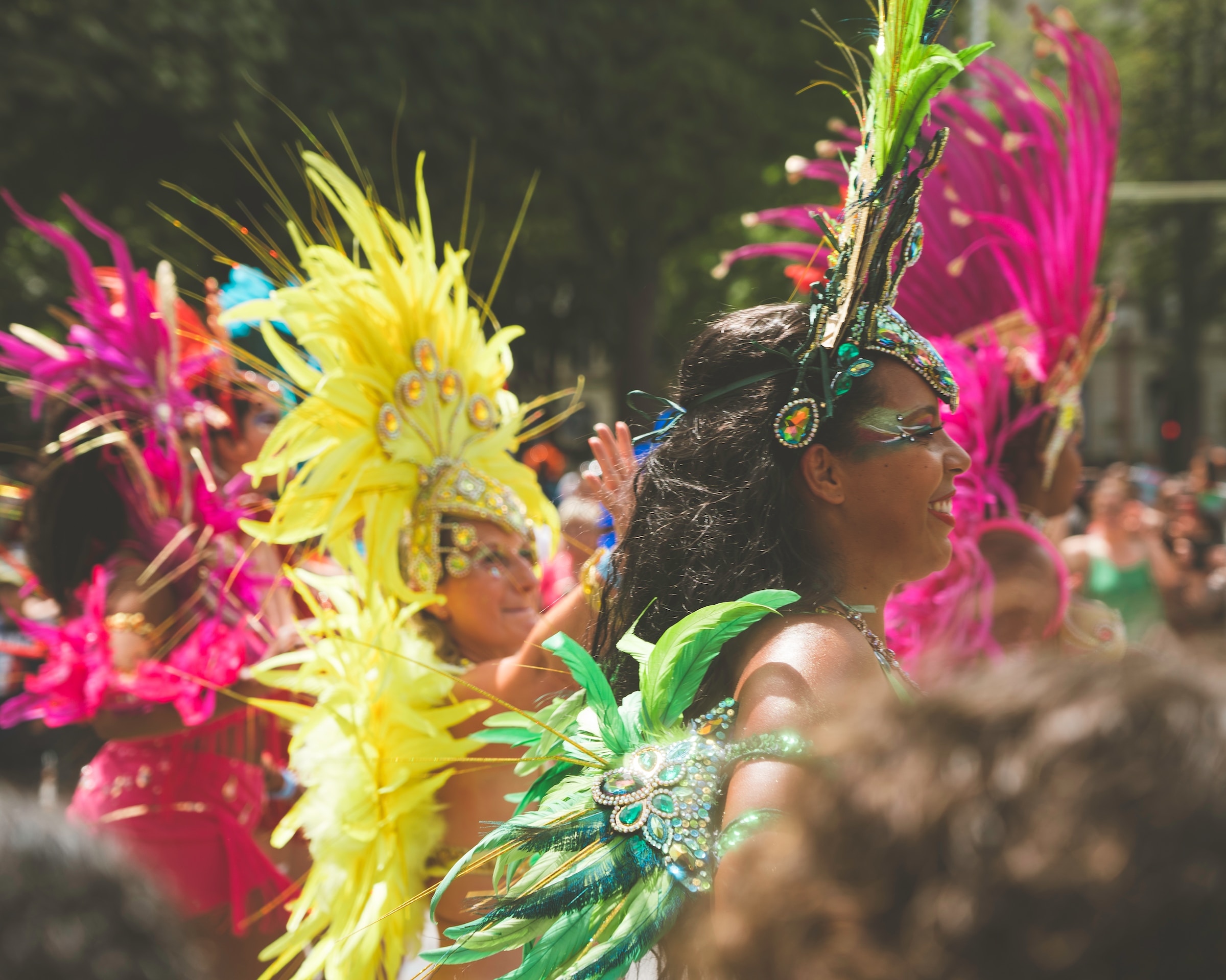 Side View of Women in colorful feathered Carnival costumes captured between masqueraders during a parade
