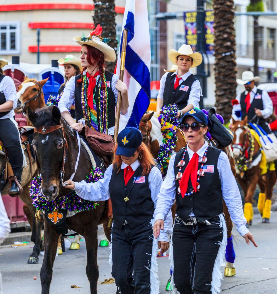 Group riding on horses passing through the parade route at Lafayette Mardi Gras