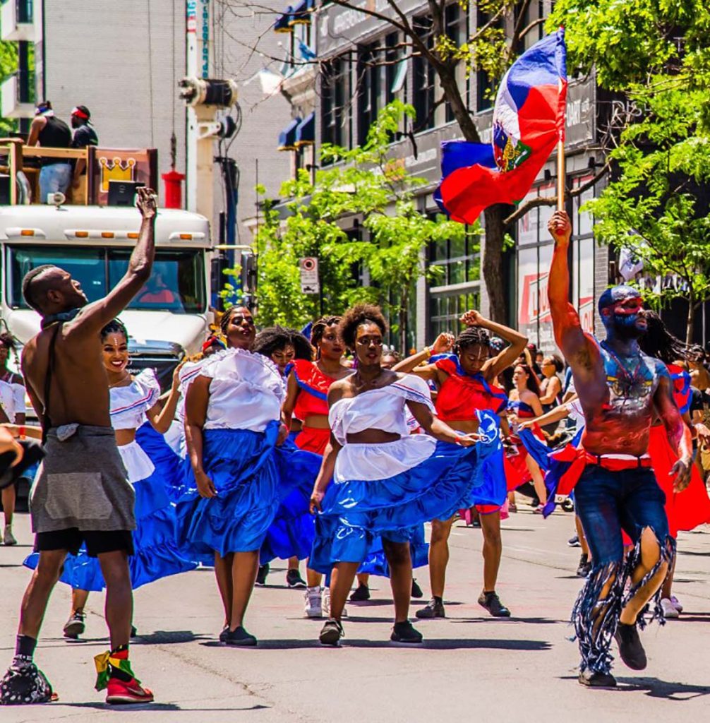Haitian masqueraders in colorful costumes performing at a Carnival parade in Montreal