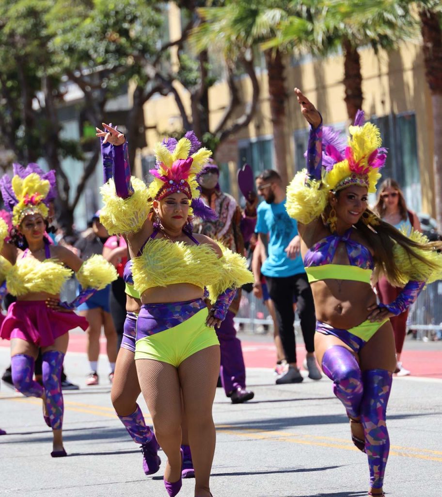 Group of women in colorful costumes dancing on the street at Carnaval San Francisco parade