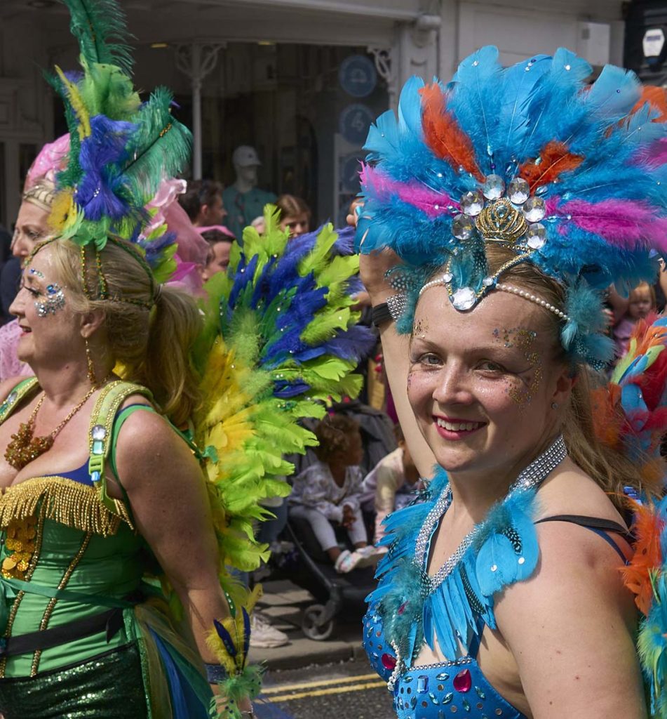 Woman in colorful costume smiling for the camera while dancing at Bishop’s Stortford Carnival