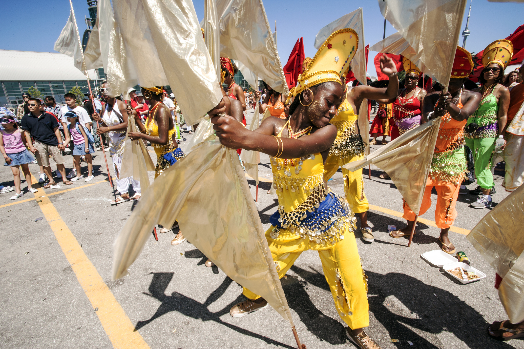 Before the actual start of the annual main Toronto Caribana, or summer carnival, parade in the marshalling area for parade floats, this very engaged yellow princess and her group are getting ready to join the parade. These moments are often as interesting as the main parade activity on the parade floats. Toronto Caribana is a major North Amercan human rights, diversity and cultural event for Caribbeans, African Canadians and Black Americans, attracting many tourists and visitors.