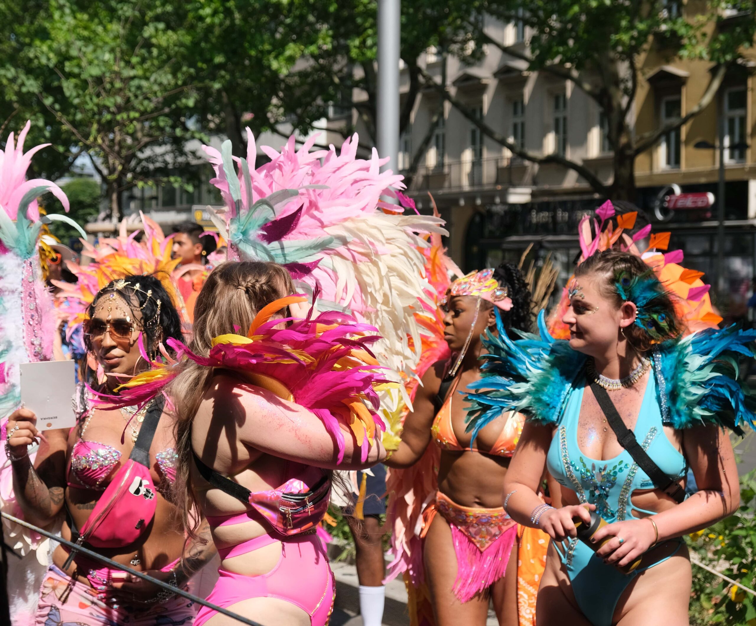Women in colorful Carnival costumes dancing and celebrating at the Vienna Carnival Road March on July 6, 2025.