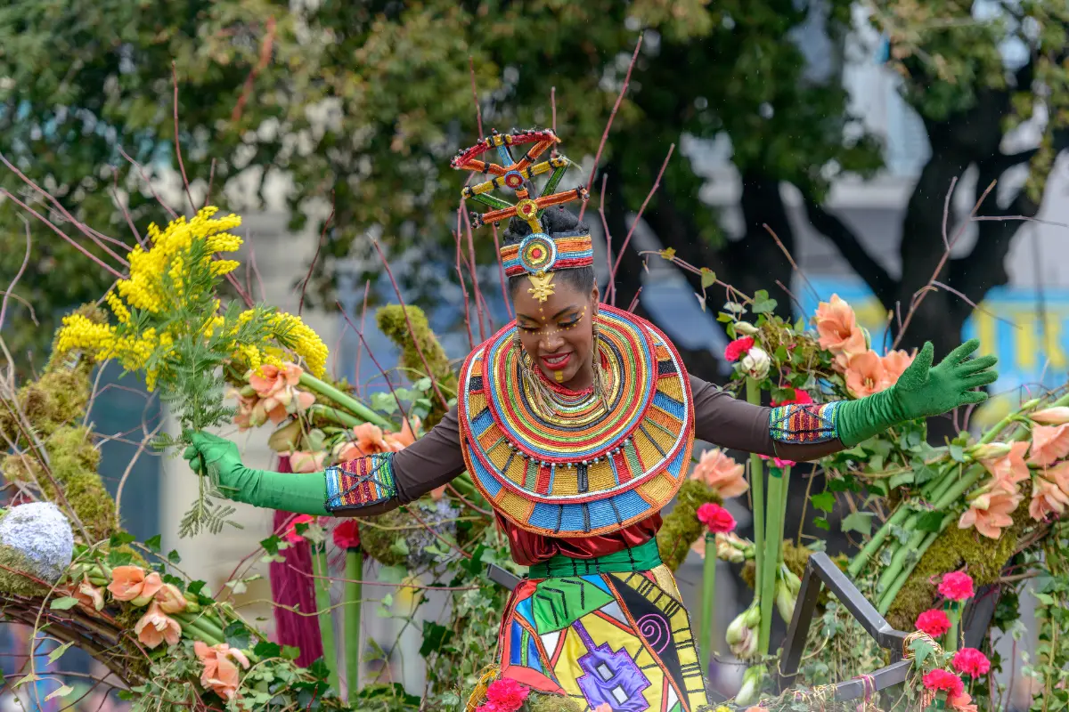 Woman in colorful African-inspired costume performing on a flower-covered float during Carnaval Tropical de Paris in Paris, France.