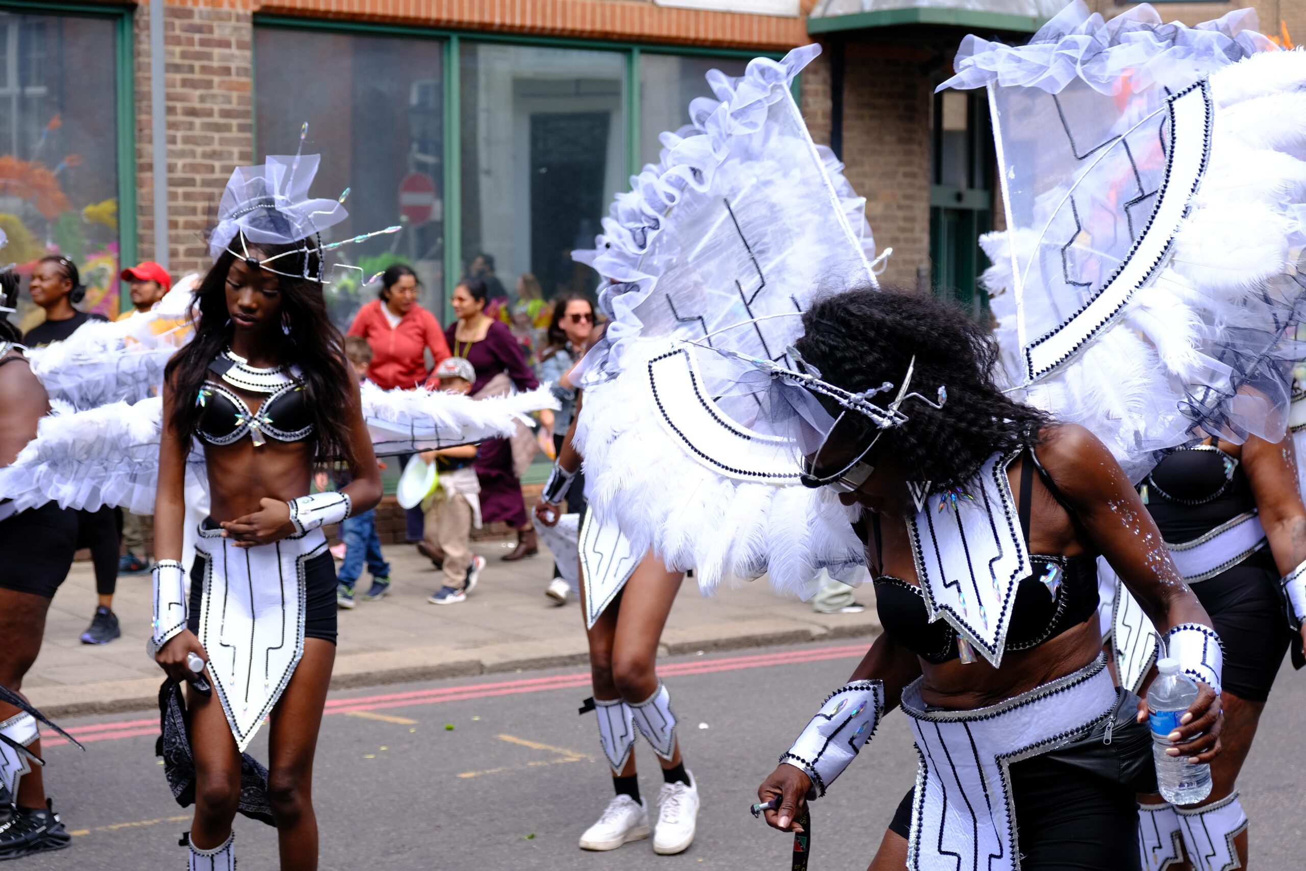 Female masqueraders in vibrant Carnival costumes dancing and enjoying the road at Luton International Carnival 2025 in the UK.