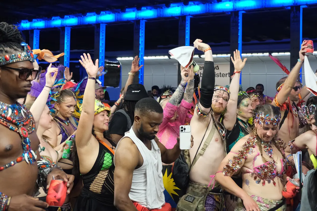 Crowd of revelers dancing in colorful carnival costumes under blue lights during Munich Carnival in Germany.