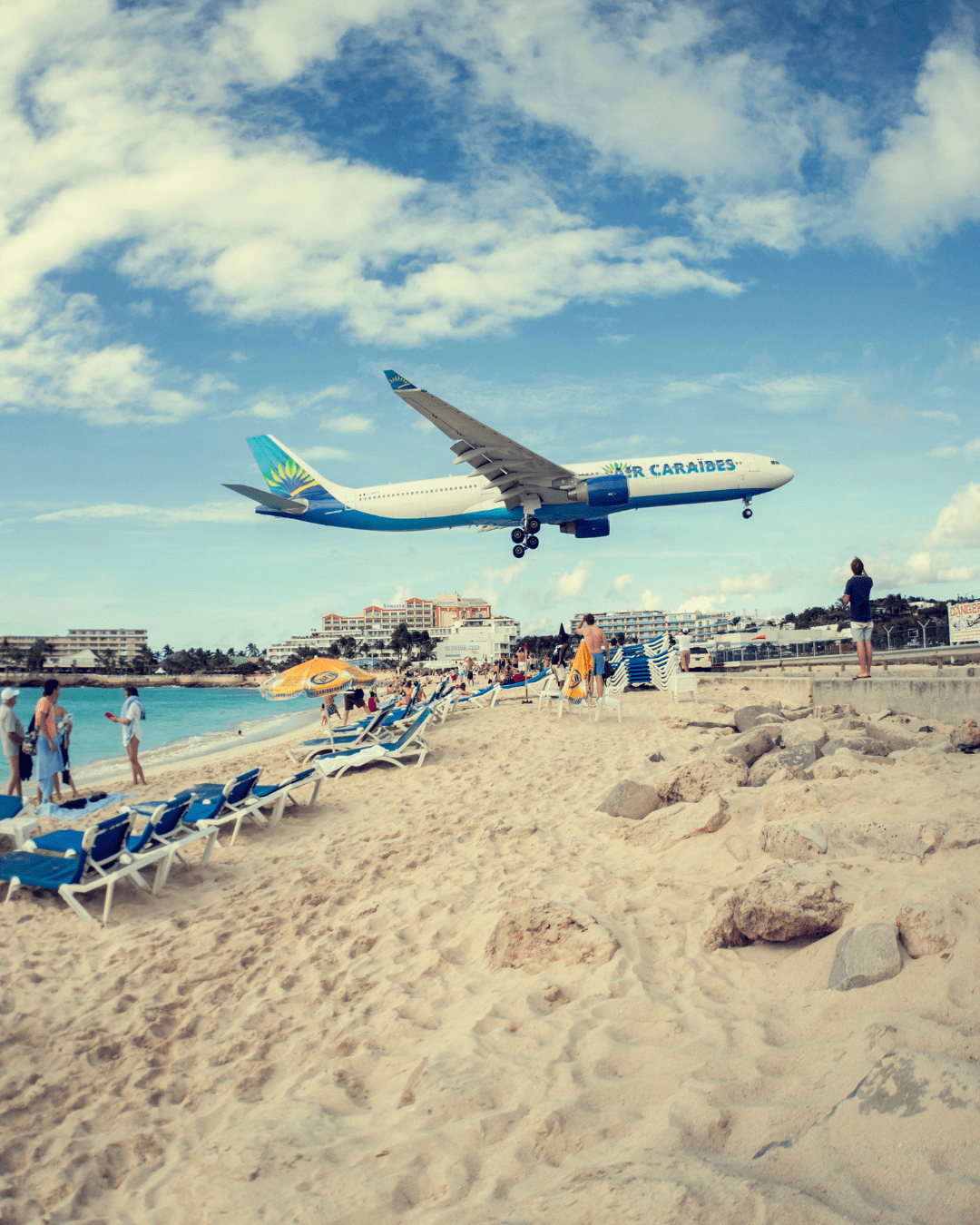 Air Caraïbes commercial plane landing at Maho Beach in St. Maarten with crowds on the sand watching. Popular spot for visitors coming to SXM Carnival 2026.