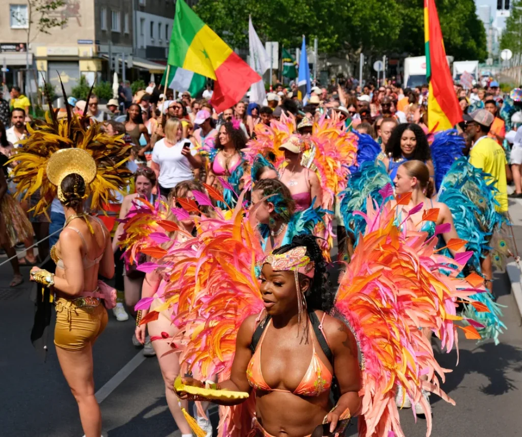 Colorful masqueraders in feathered backline costumes parading through Vienna Carnival street celebration, showcasing international carnival terms in action.