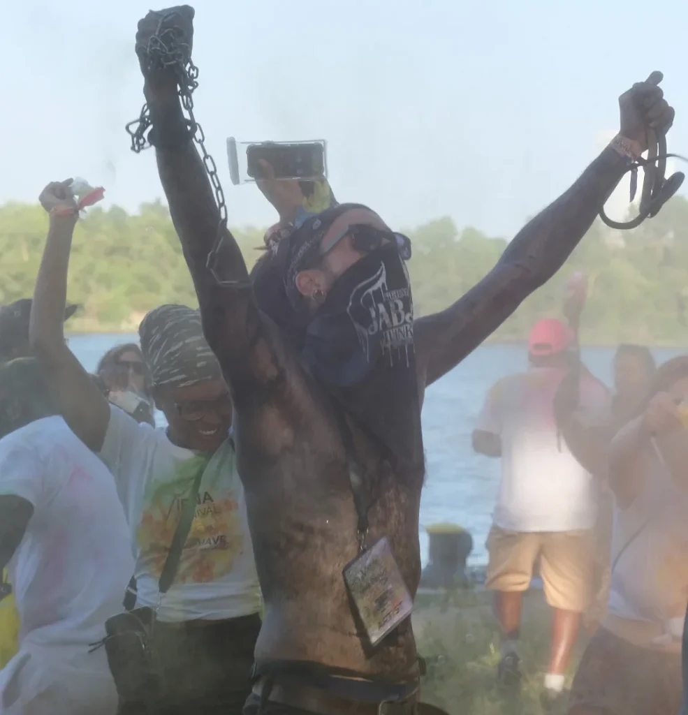 Carnival reveler covered in paint and powder celebrating J’Ouvert-style festivities, highlighting traditional Caribbean carnival terms and rituals.