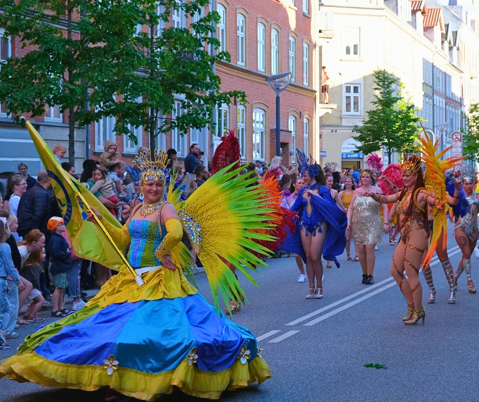 Colorful dancers in feathered costumes entertaining crowds at Aalborg Karneval in Aalborg city center.