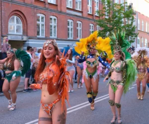 Feathered dancers performing in open-air setting during Aalborg Karneval celebration.