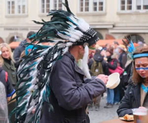 Masopust festival attendees in costume enjoying traditional Czech street food from bowls and plates during the lively celebration.