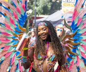 Hotels near Notting Hill Carnival with colorful masquerader in feathered costume celebrating during the London street parade