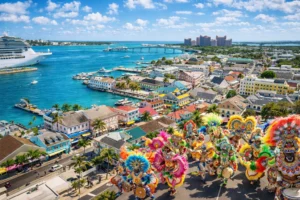 Aerial view of downtown Nassau during Bahamas Carnival with colorful Junkanoo masqueraders, pastel colonial buildings, and turquoise harbor waters.