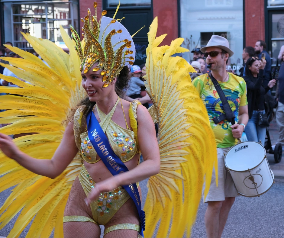 Carnival dancer wearing a yellow feather costume and headdress performing in the Aalborg Carnival parade in Aalborg, Denmark.