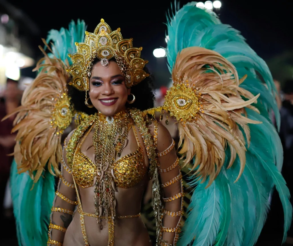 Female samba dancer wearing an elaborate gold carnival costume with turquoise feather wings during the Rio Carnival parade in Rio de Janeiro, Brazil.