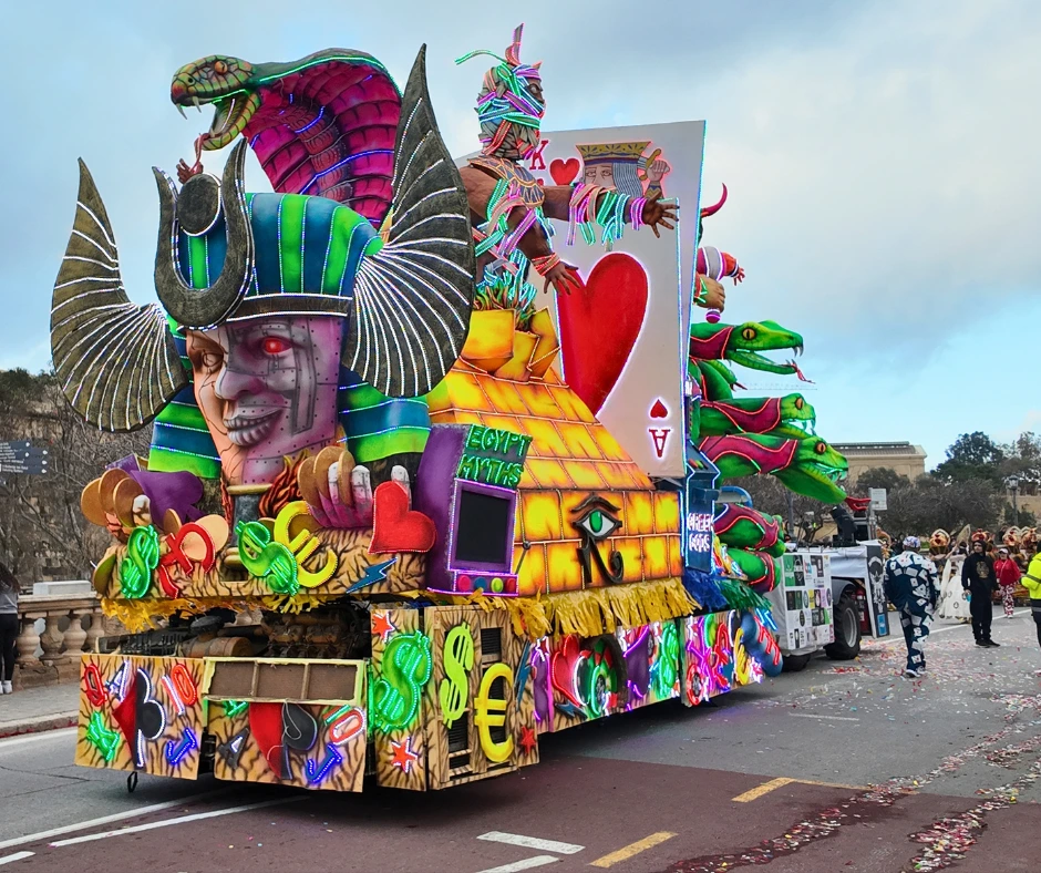 Colorful parade float with neon designs, masks, and mythical figures during carnival in Malta celebrations