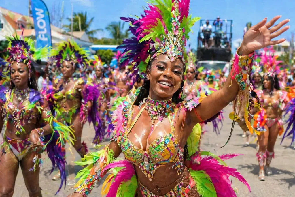 Smiling female masquerader in bright feather carnival costume waving during Anguilla Summer Festival road march in The Valley