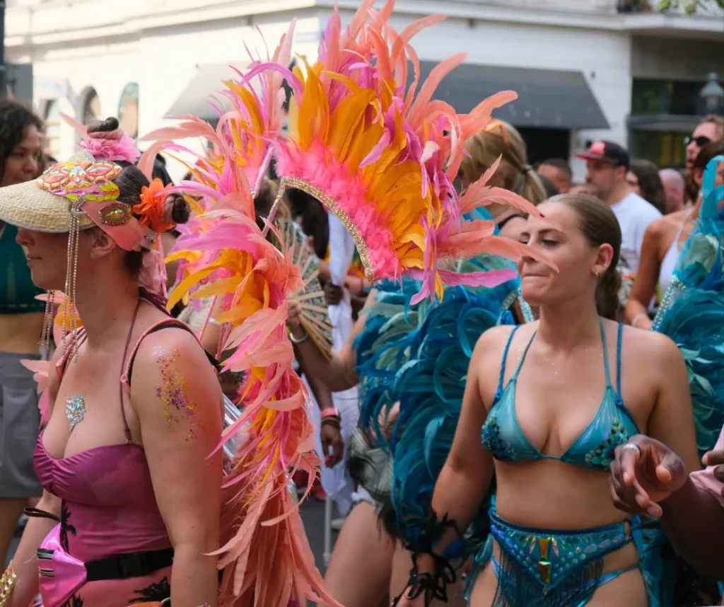 Close-up of carnival masqueraders wearing vibrant feathered costumes and beaded bikinis, highlighting details to consider when choosing how to get a carnival costume