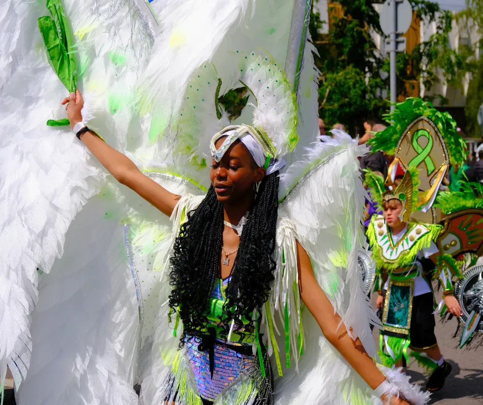 Carnival participant wearing a large feathered wing backpack costume in green and white, showing premium costume options when deciding how to get a carnival costume