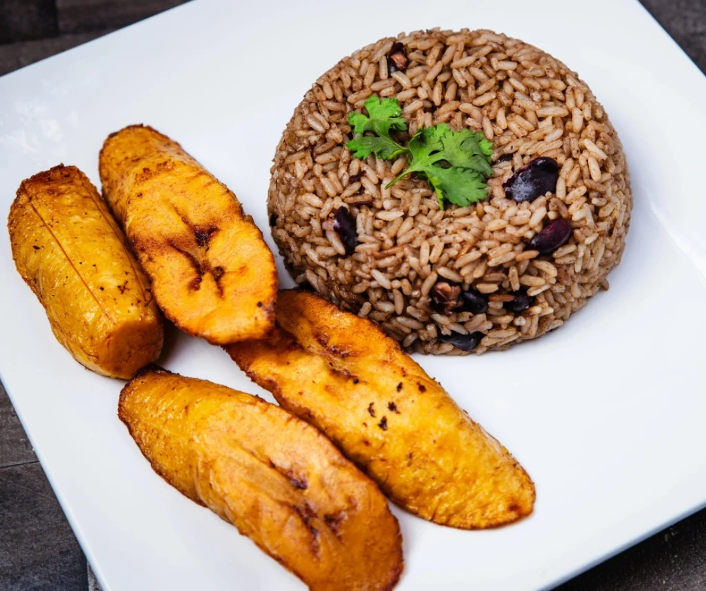 Caribbean rice and peas served with fried plantains on a plate