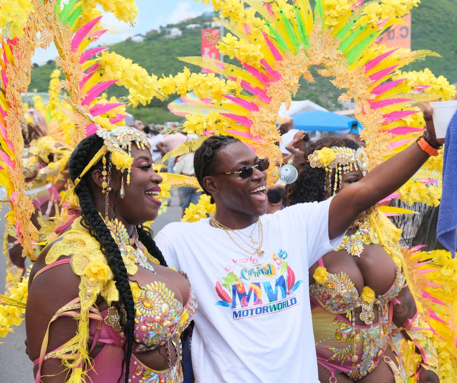 Man taking selfie with women in yellow feather costumes during SXM Carnival 2026 Grand Parade in St Maarten