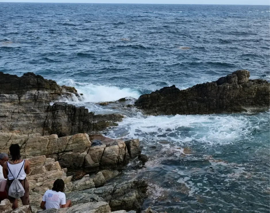 Hikers look out over the rocky coastline and natural pool during a Pointe Blanche hike in St. Maarten.