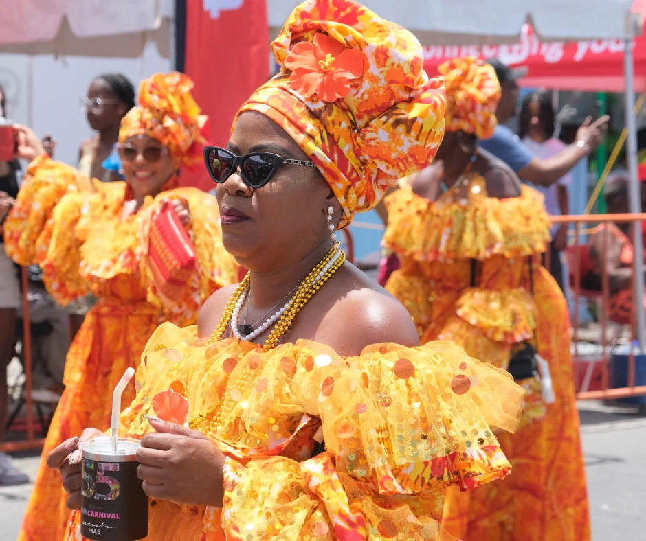 A carnival participant wears a vibrant yellow and orange traditional costume during SXM Carnival 2026 celebrations.