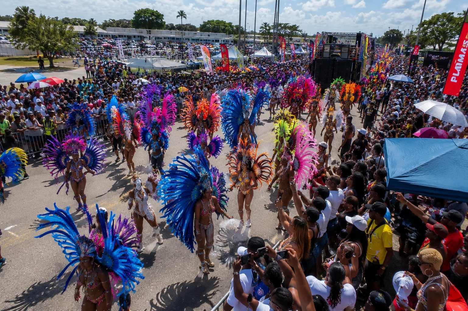 AI-generated aerial illustration of Miami Carnival at the fairgrounds showing masqueraders, music trucks, and roadside spectators during one of the largest events on the list of Caribbean carnivals.