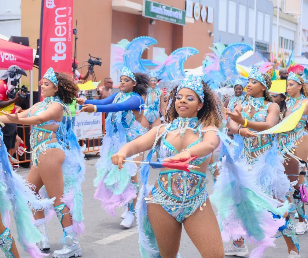 Group of women in blue feather costumes dancing in formation at SXM Carnival 2026 Grand Parade in St Maarten