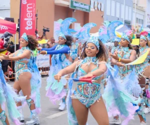 Group of women in blue feather costumes dancing in formation at SXM Carnival 2026 Grand Parade in St Maarten