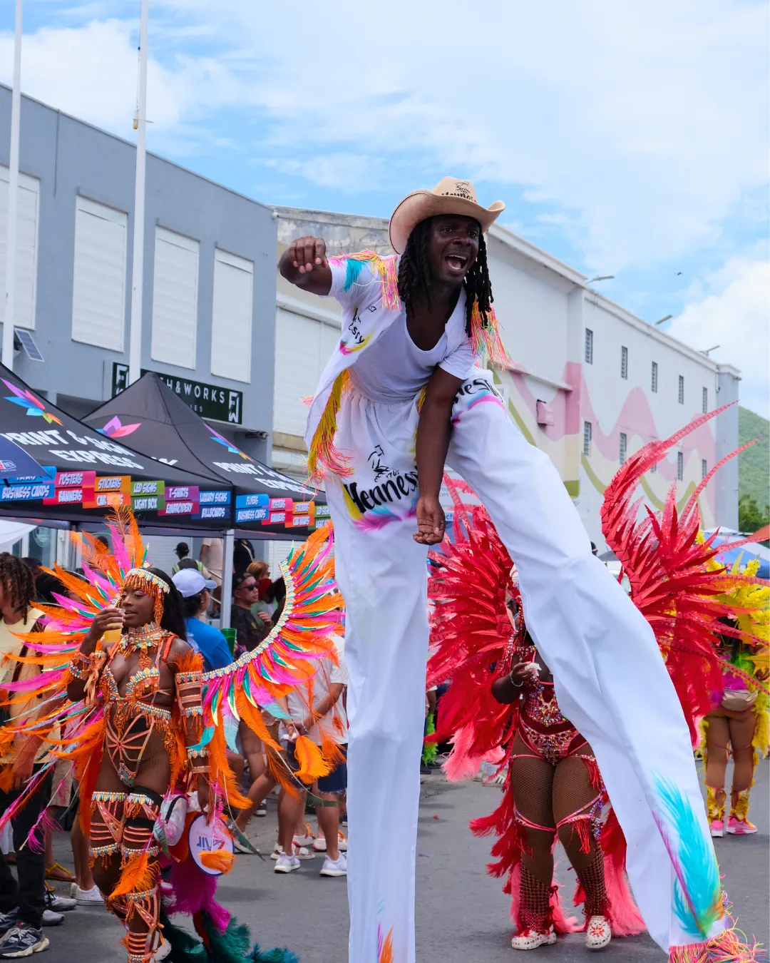 Stilt walker and masqueraders celebrating at Caribbean carnival, featured as a carnival travel resource