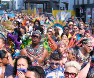 Large crowd of masqueraders in colorful feathered costumes and jeweled accessories at the Munich Carnival 2026 road march
