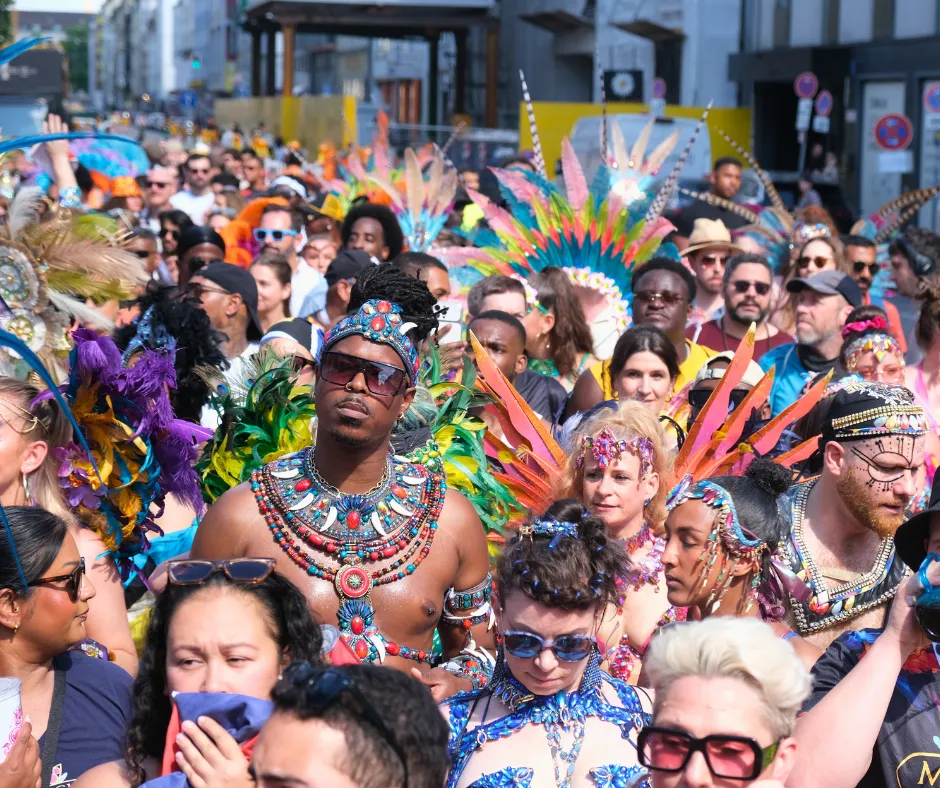 Large crowd of masqueraders in colorful feathered costumes and jeweled accessories at the Munich Carnival 2026 road march