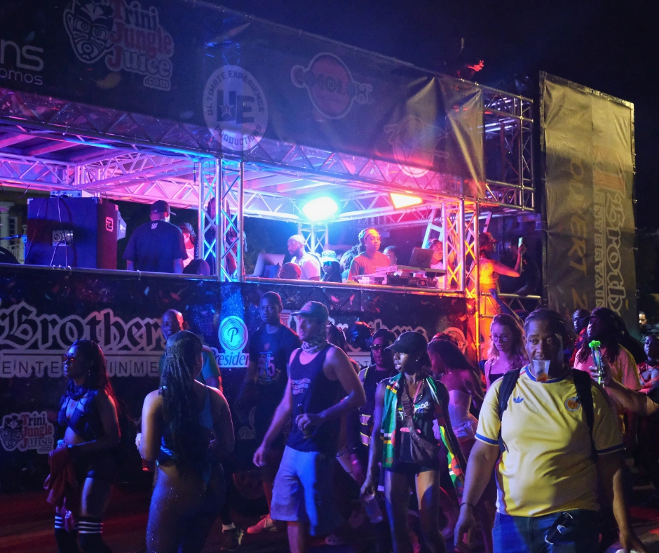 Revelers walking beside a music truck during Jouvert Carnival celebrations at night