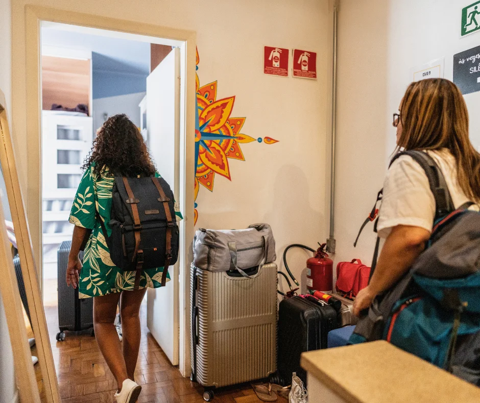 Travelers with luggage checking into a rental, representing affordable accommodation when planning where to stay for carnival.