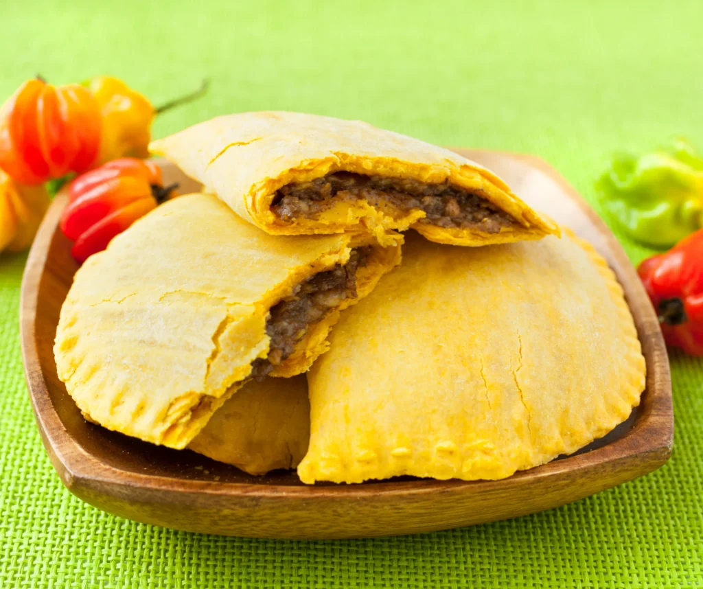Jamaican beef patty served on a wooden plate, one of the popular Caribbean foods at carnival