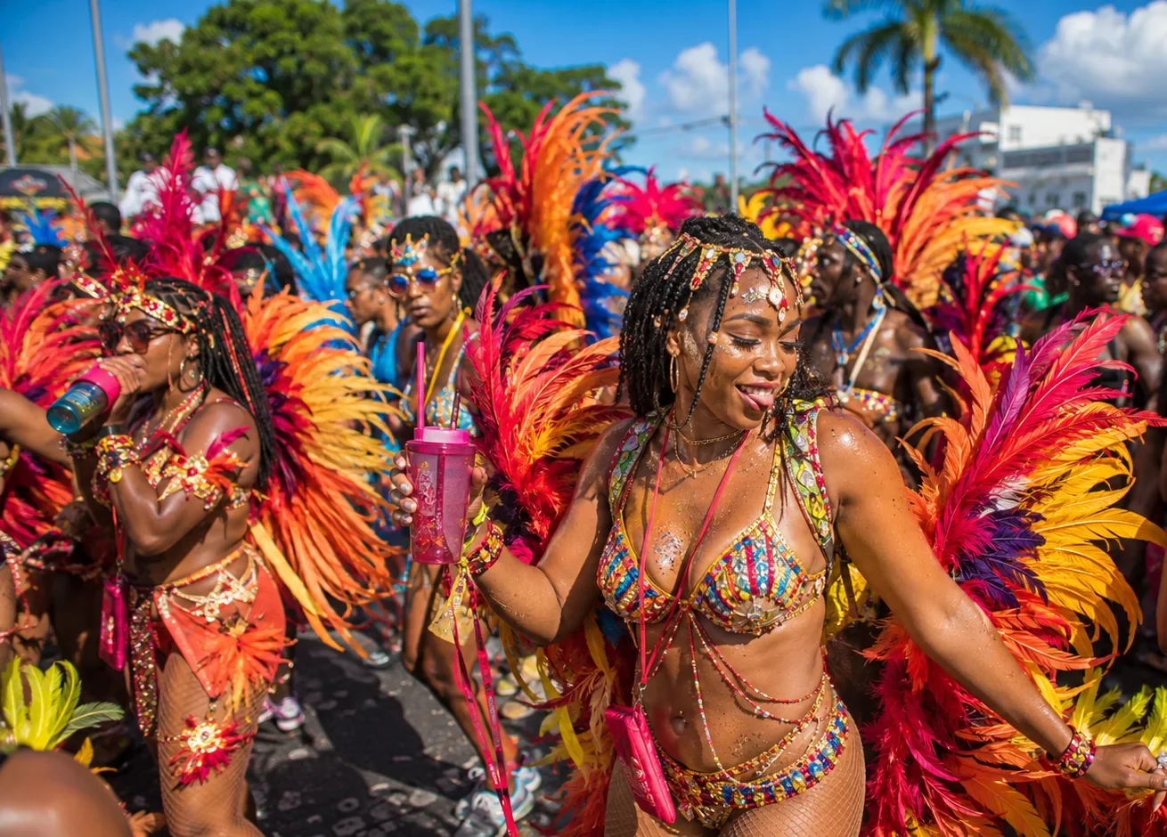 Woman in a colorful feathered carnival costume dancing at Barbados Grand Kadooment Day