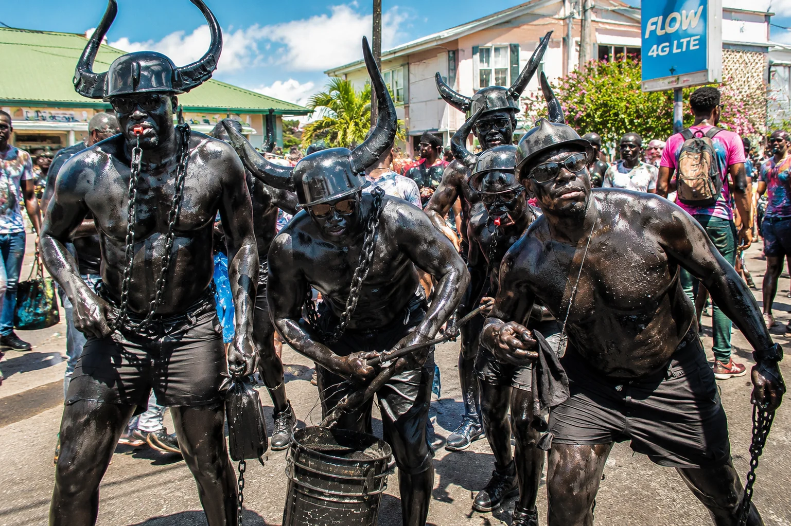 Jab Jab carnival masqueraders covered in black paint and wearing horned helmets parade through the streets of Grenada.