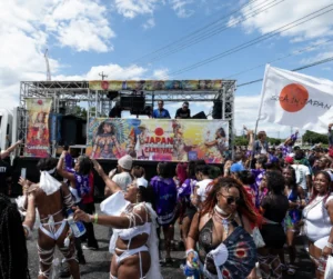 Japan Caribbean Carnival crowd dancing in front of a Soca in Japan music truck with carnival flags, DJs, costumes, and revelers celebrating outdoors.
