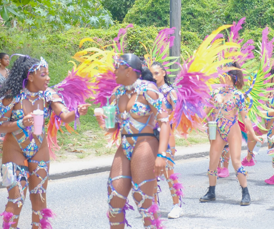 Masqueraders in gem-encrusted pretty mas costumes with pink, yellow and green feathered wings playing mas on the road at SXM Carnival