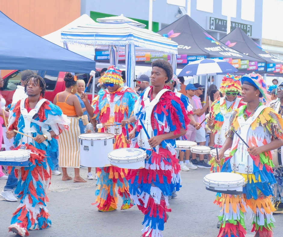 Young drummers in bright multicoloured fringed costumes performing on the road march at SXM Carnival in Saint Martin