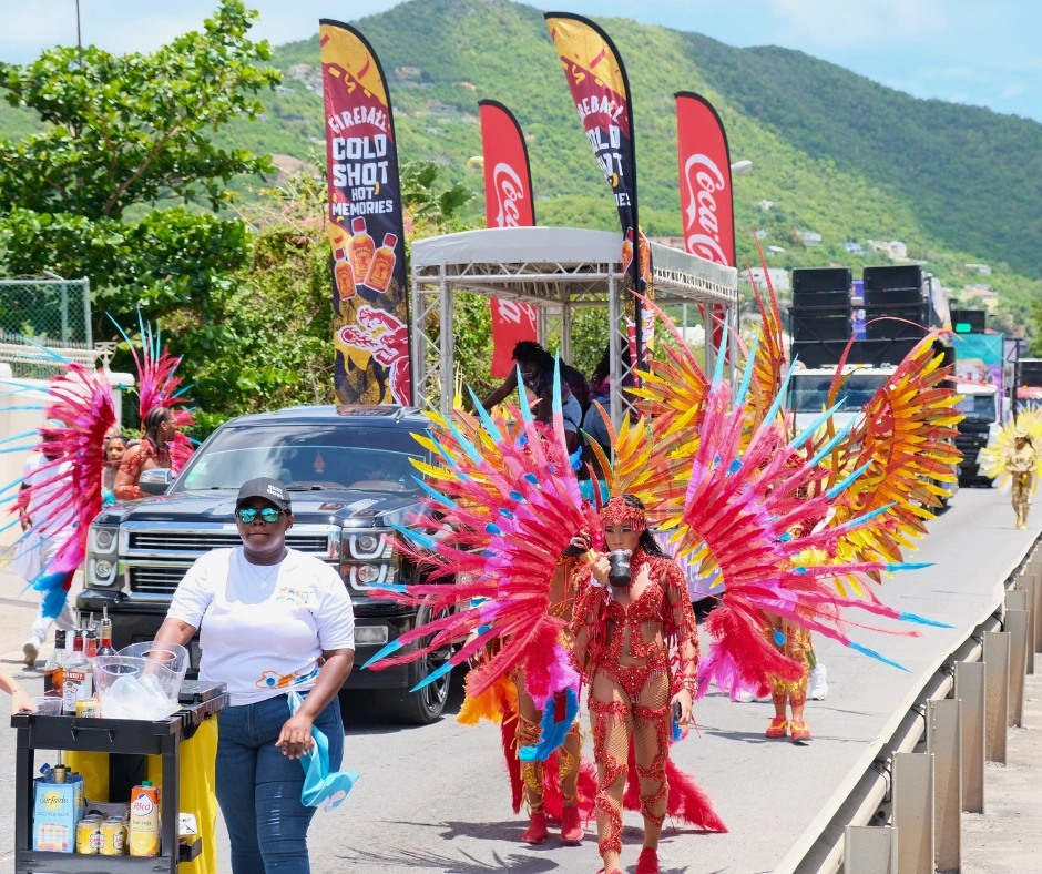 Caribbean Carnival road march at SXM Carnival with a music truck and masqueraders in multicolour feathered costumes chipping down the road