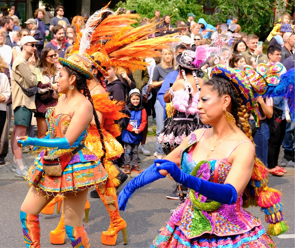 South American carnival dancers in ornate feathered and sequined costumes performing in front of a large crowd at the Berlin Carnival of Cultures