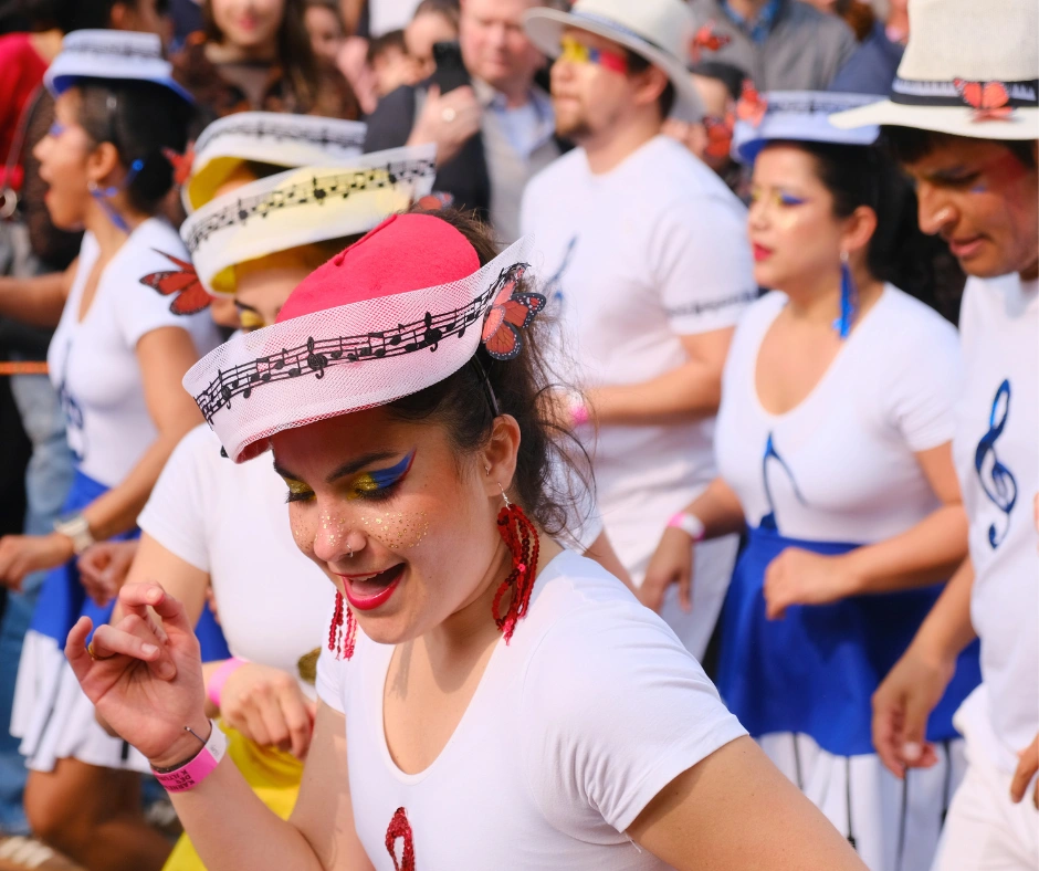 Dancers in matching white Colombian style costumes with music note details performing at the Berlin Carnival of Cultures