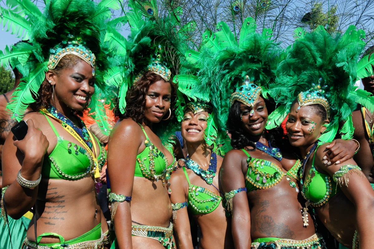 Five masqueraders in matching green feather headdresses and jewelled costumes posing together on the road at Caribbean Carnival.