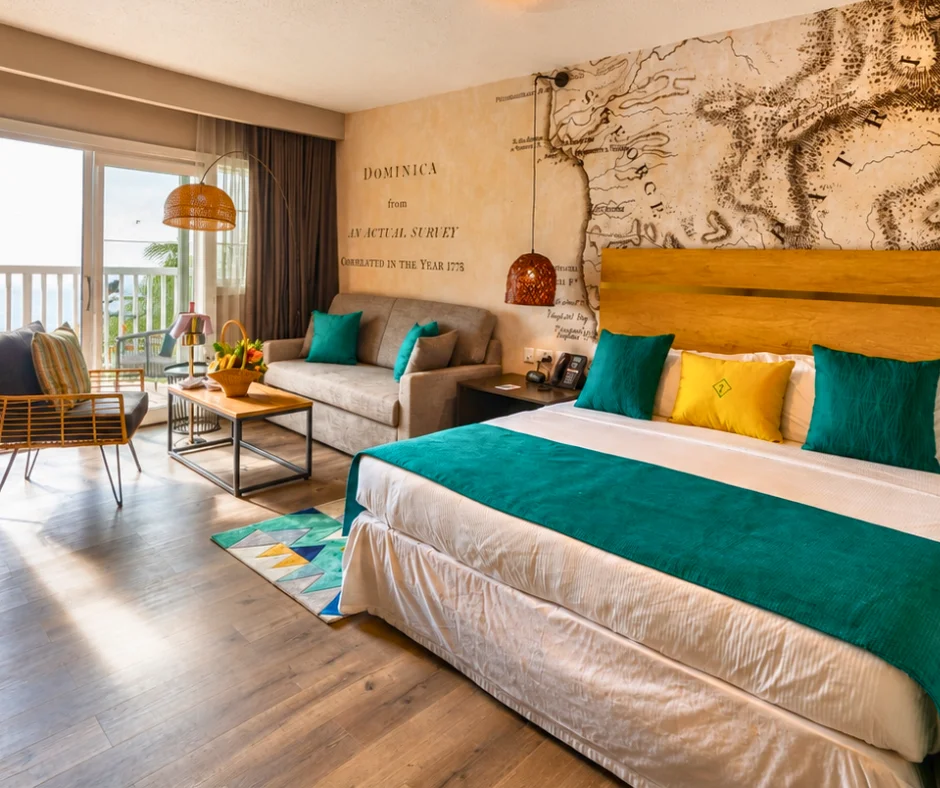 Guest room at Fort Young Hotel with a historic Dominica map mural and sea-view balcony, one of the Dominica Carnival hotels closest to the Roseau parade route.