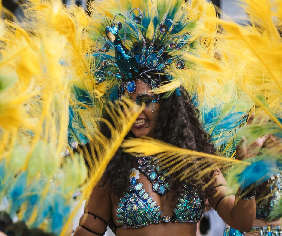 Masquerader in a turquoise and yellow feathered headdress and jewelled costume, framed by tall yellow plumes