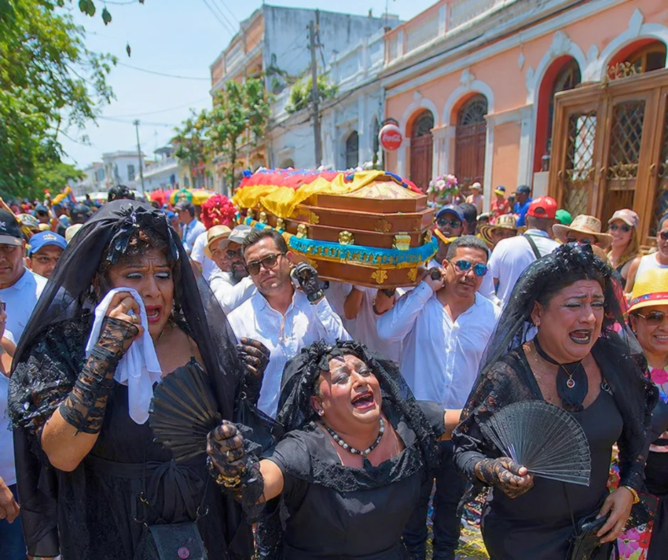 Costumed mourners in black lace veils carry an ornate coffin through the streets of Barranquilla during the Burial of Joselito Carnaval